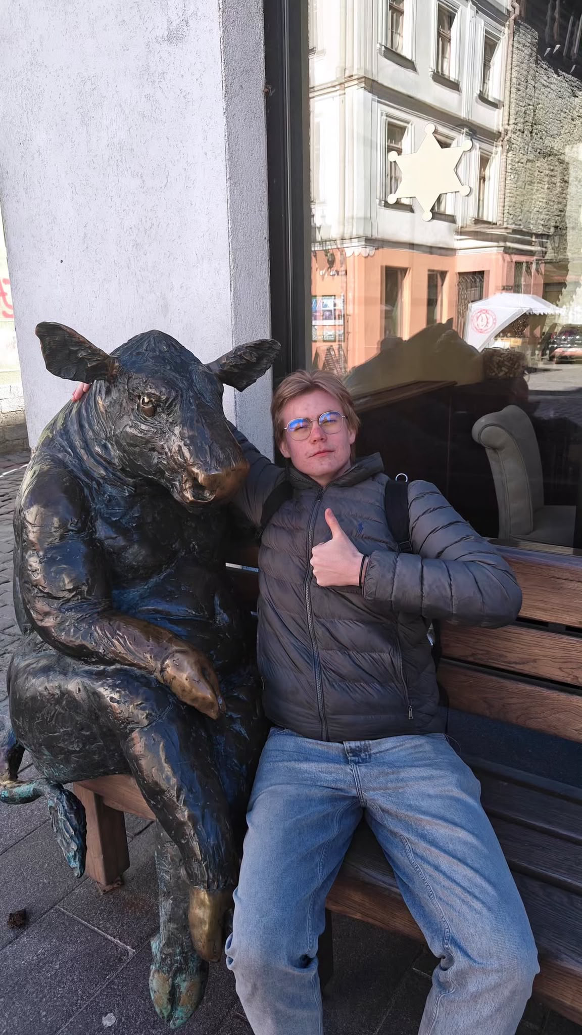 Lukas på en bänk bredvid en staty